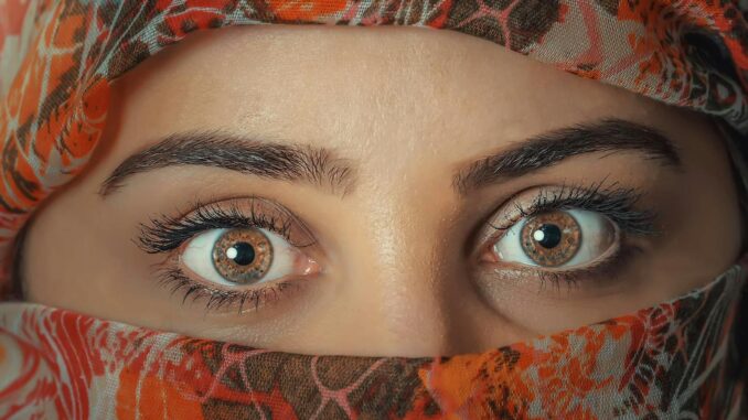 Santé visuelle Un gros plan saisissant des yeux d'une femme encadrés par un foulard coloré, capturant la beauté et le mystère.
