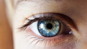 personne ouvrant son œil droit avec un iris bleu