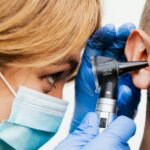 Gros plan d'un médecin effectuant un examen de l'oreille avec un otoscope.