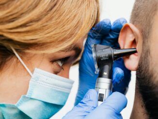 Gros plan d'un médecin effectuant un examen de l'oreille avec un otoscope.