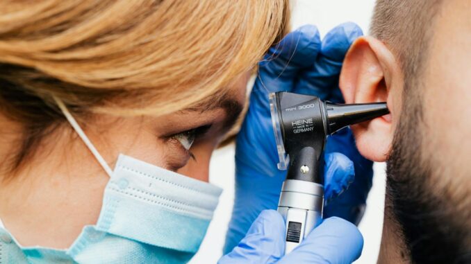 Bilan auditif Gros plan d'un médecin effectuant un examen de l'oreille avec un otoscope.