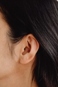 Image détaillée en gros plan présentant une oreille humaine et des cheveux foncés.